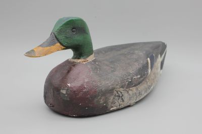 un gros plan d'un canard en bois posé sur une surface blanche