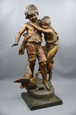 statue en bronze représentant un garçon et une fille avec un oiseau