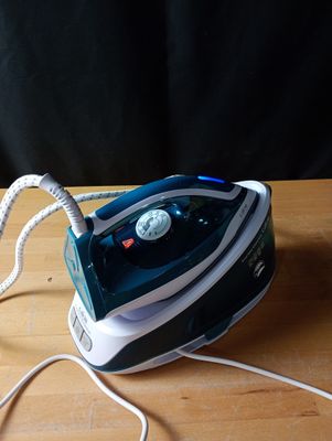 un fer à repasser à vapeur bleu et blanc posé sur une table en bois