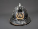 an old fireman ' s helmet with a gold emblem on it