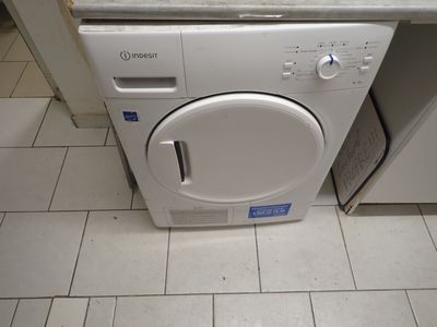 une machine à laver et un sèche-linge blancs posés sur un sol carrelé