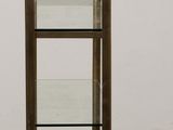 an image of a glass and brass display case on a wooden floor