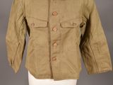 une vieille veste militaire posée sur un mannequin, devant un fond gris