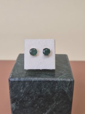 a pair of green jade stud earrings sitting on top of a marble block