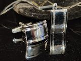 pair of silver cufflinks sitting on top of a table next to a bag