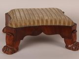 un petit tabouret en bois surmonté d'un coussin rayé
