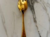 a gold spoon sitting on a marble counter top