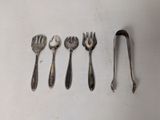 five spoons and a fork on a white surface