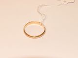 une bague en or suspendue à un fil sur une table blanche