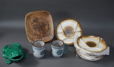 plusieurs pièces de poterie posées sur une table, à côté d'une grenouille