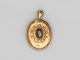 un gros plan d'un pendentif en or orné d'une pierre violette