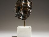 une image représentant une sculpture en bronze représentant le visage d'un homme, posée sur un socle en marbre
