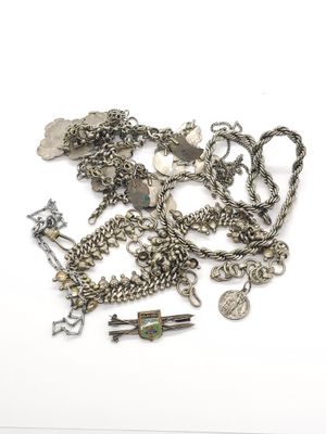 un tas de bijoux en argent posés sur une surface blanche