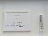 un flacon de parfum posé à côté d'une carte sur une étagère