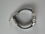 a silver bracelet with a black band on a white surface