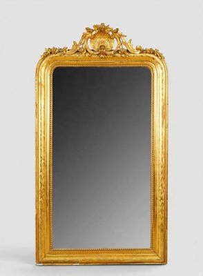 un miroir à cadre doré posé sur un mur blanc