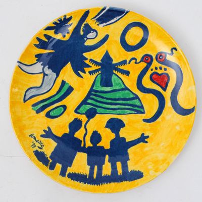 une assiette jaune sur laquelle est représentée une sorcière et deux enfants