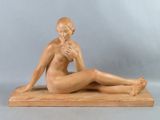 sculpture représentant une femme nue assise sur un socle en bois, les jambes croisées
