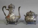 paire de théières anciennes en argent sur un socle, sur fond gris
