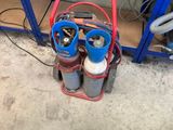 a red cart with two gas bottles on it in a garage