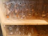many empty wine glasses on a shelf in the kitchen