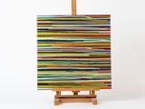 tableau aux couleurs vives posé sur un chevalet, sur fond blanc