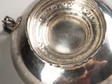 a silver bowl on a white surface with a chain around it