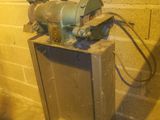 une machine posée à même le sol, à côté d'un mur de briques