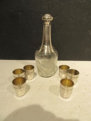 une bouteille en verre et quatre verres à shot posés sur une table