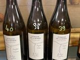 trois bouteilles de vin sont posées sur une table en verre devant un tableau