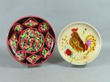 two plates with designs of roosters and flowers on them