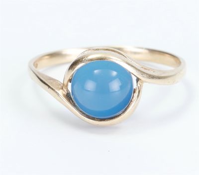 a close up of a gold ring with a blue stone