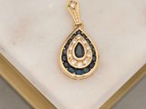 an image of a diamond and sapphire tear pendant on a marble surface
