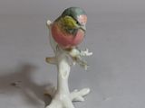 a small figurine of a bird sitting on a branch