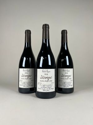 trois bouteilles de vin rouge sont posées sur une surface blanche