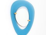 un miroir accroché au mur, orné d'un triangle bleu