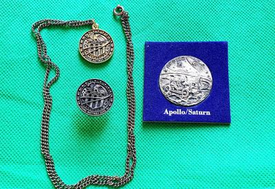 un collier en argent et une pièce d'argent posés sur un tissu vert