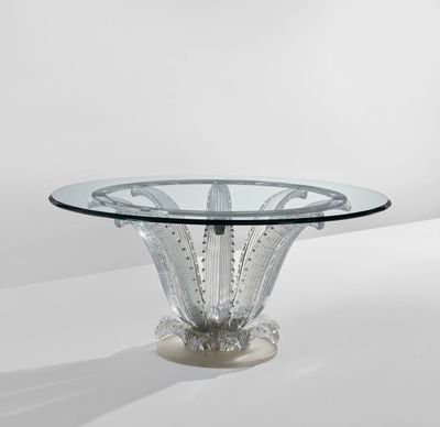 une table ronde en verre avec un piètement en métal et un plateau en verre transparent