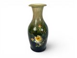 a green vase with flowers painted on it on a white background