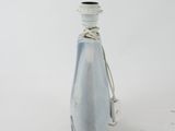 a glass bottle with a rope around it on a white surface