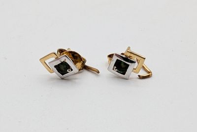 a pair of gold and silver cufflinks with a green stone