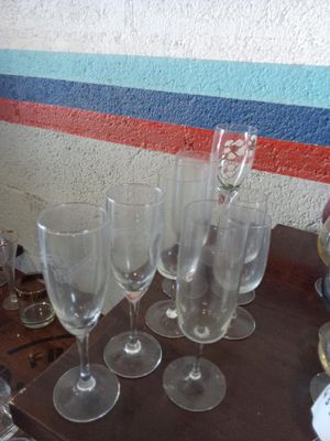 Plusieurs verres à vin vides sont posés sur une table devant un mur.