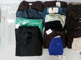 Plusieurs paires de pantalons et de chaussures sont disposées sur une table