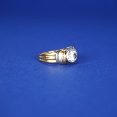 un gros plan d'une bague en or et diamants sur fond bleu