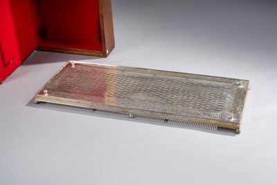 un plateau en argent posé sur une surface blanche, à côté d'une boîte rouge