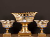 trois vases dorés posés sur une table, sur fond noir