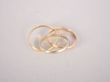 two gold wedding rings sitting on top of each other on a white surface