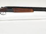 le fusil est posé sur un support transparent, sur une surface blanche