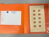un classeur orange contenant des timbres et une carte