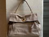un sac à main en cuir beige accroché au mur devant une porte